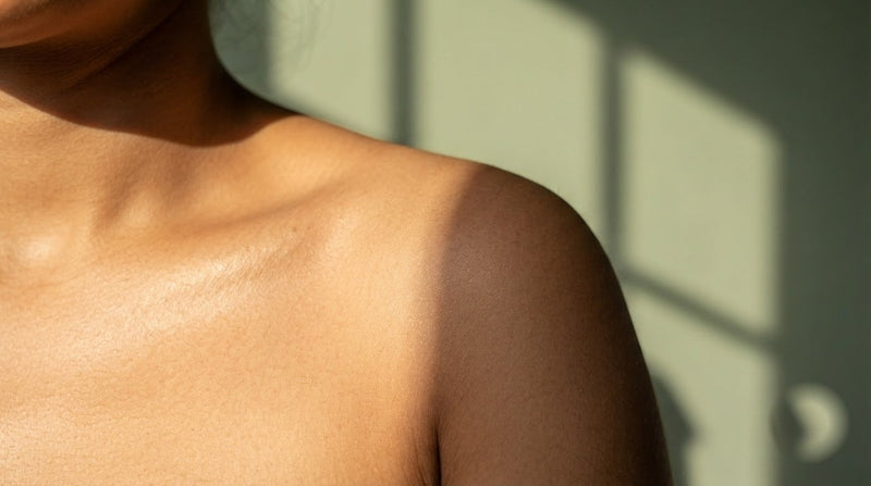 Window light and shadow falling across a bare shoulder