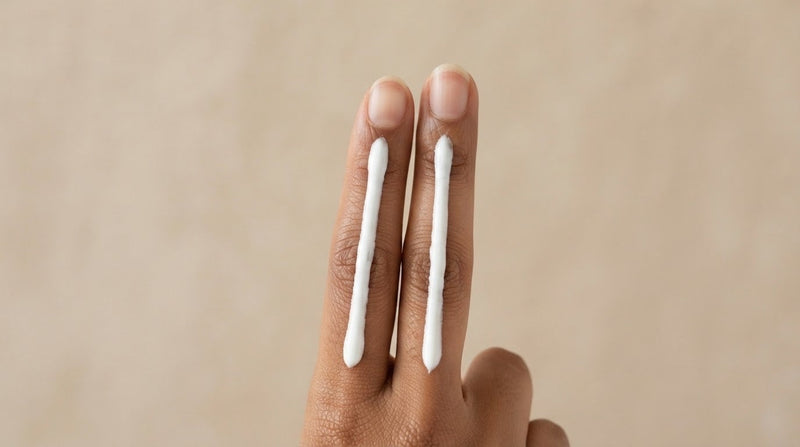 Two fingers carrying lines of white sunscreen